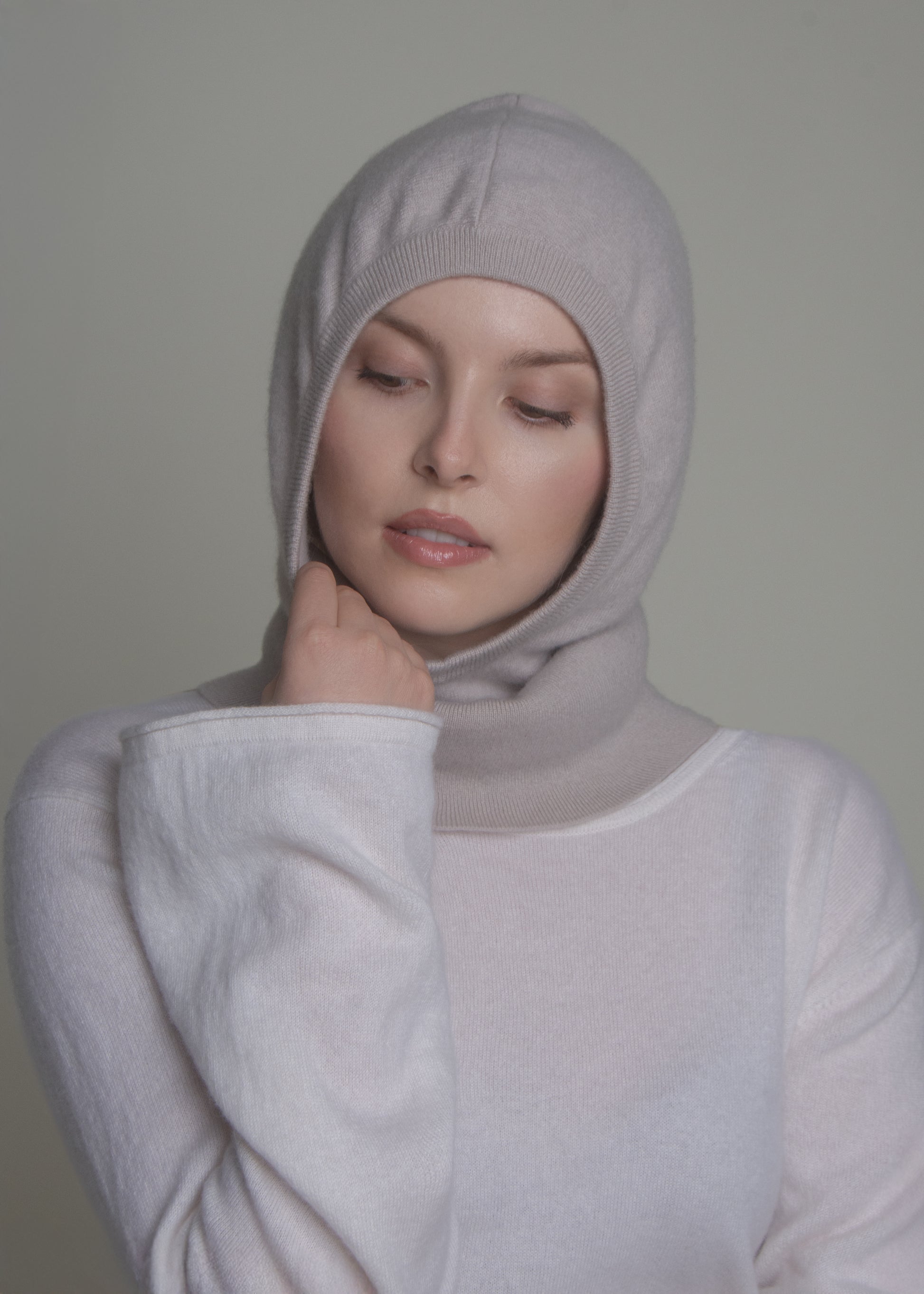 woman wearing light cashmere balaclava hood with hand on cheek