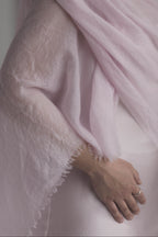 Woman wearing a light pink scarf and silk dress against a neutral background