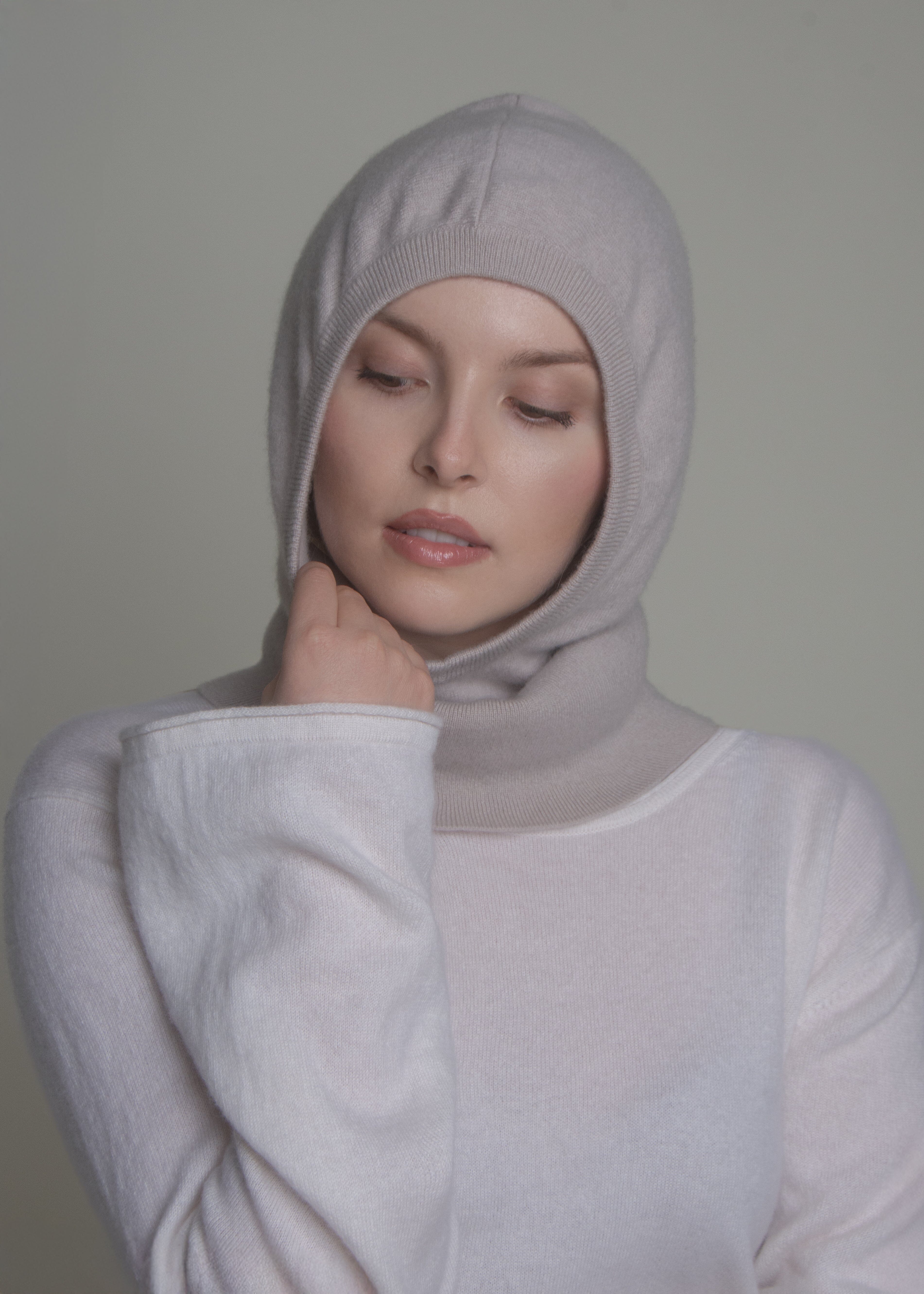 woman wearing light cashmere balaclava hood with hand on cheek